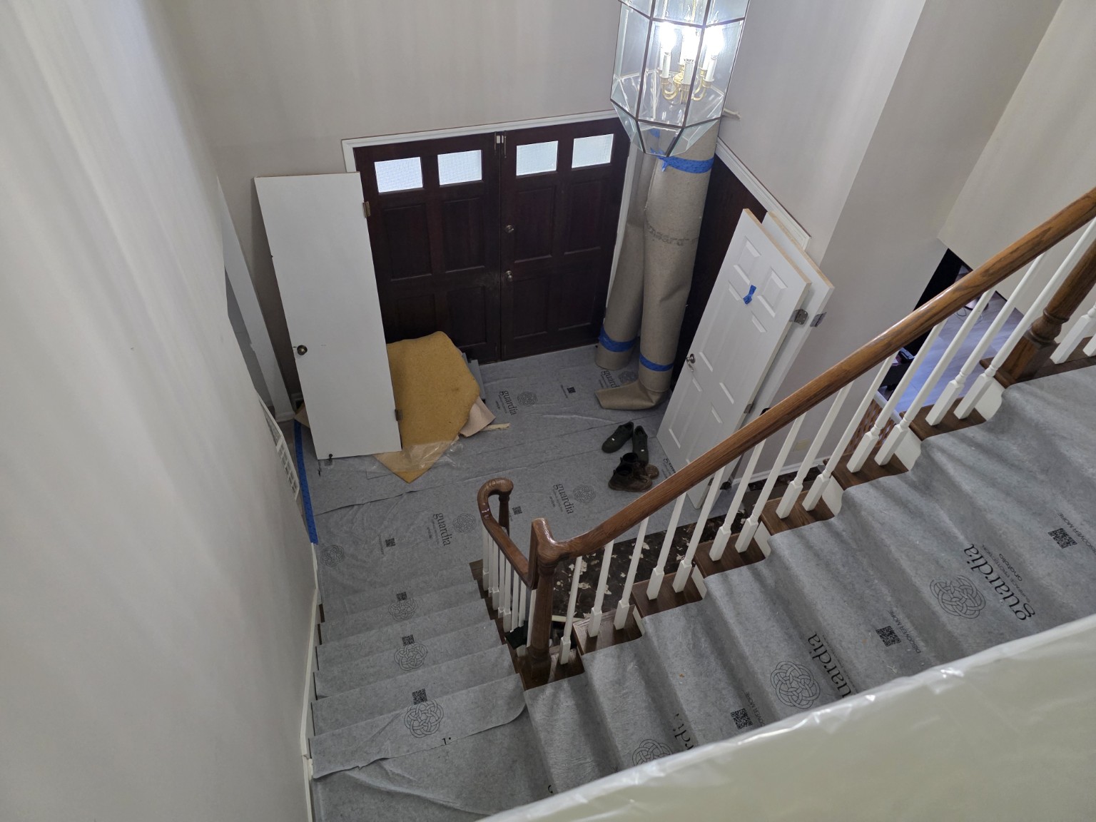 Protective floor coverings across an entry and stair landing before demolition