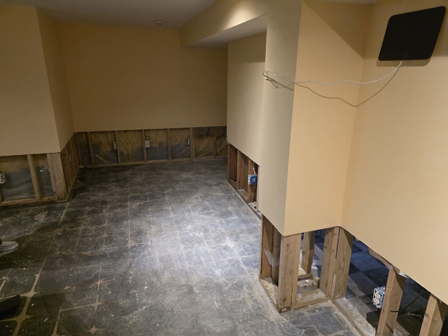 Lower-level room with wall finishes removed to expose framing